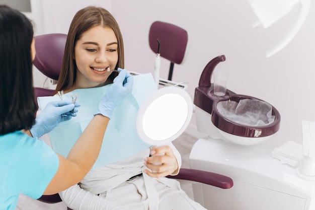 Een vrouwelijke tandarts helpt haar patiënt de kleur van het implantaat of de kroon te kiezen met behulp van een kleurenschaal