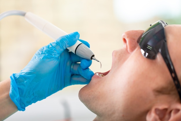 Een vrouwelijke tandarts onderzoekt de mondholte van de patiënt met een hulpmiddel met een spiegel