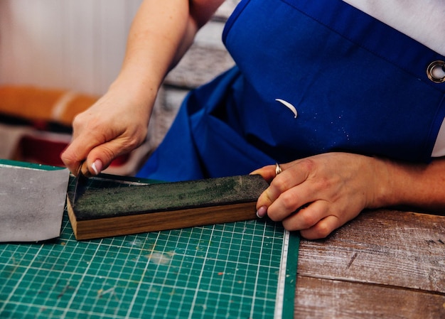 Een vrouwelijke timmerman scherpt gereedschap voor het snijden van hout met een mes in een timmerwerkplaats