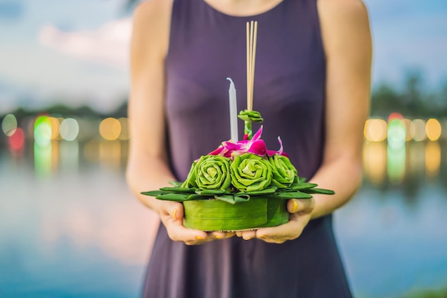 Een vrouwelijke toerist houdt de Loy Krathong in haar handen en staat op het punt hem in het water Loy . te lanceren