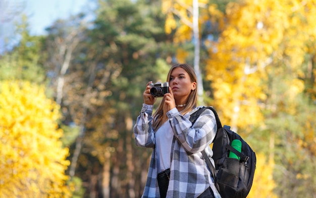 Een vrouwelijke toerist loopt in het bos met een camera en een rugzak