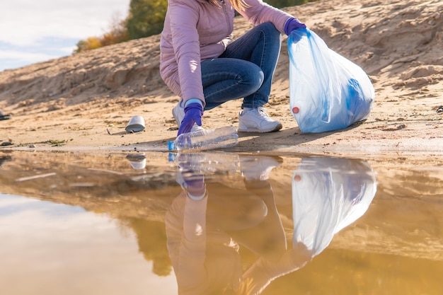 Een vrouwelijke vrijwilliger ruimt plastic afval op in de natuur.