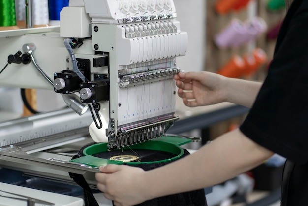 een vrouwelijke werknemer die een automatische kleermakermachine gebruikt en voorbereidt voor werk in een kledingfabriek