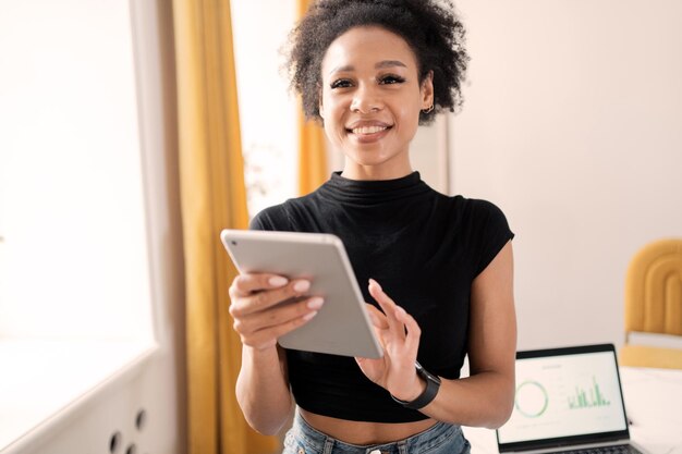 Een vrouwelijke werknemer werkt graag online in een nieuwe coworking-ruimte op kantoor met behulp van een tablet