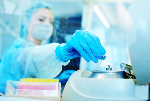 Een vrouwelijke wetenschapper in een beschermend medisch masker en rubberen handschoenen maakt PCR-DNA-tests in een modern chemisch en bacteriologisch laboratorium. 2019-nCoV; coronavirus; China;