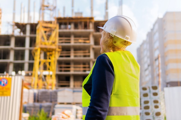 Een vrouwenbouwer op een bouwplaats inspecteert een gebouw