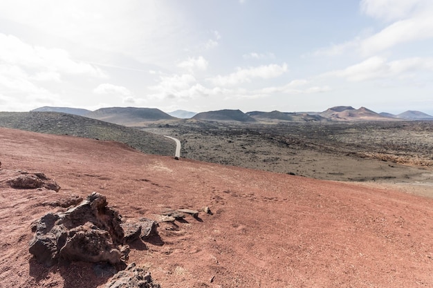 Foto een vulkanisch landschap en een weg bij het nationale park van timanfaya met vulkanen op de achtergrond in lanzarote