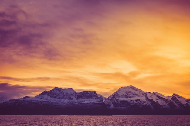 Een vurige zonsopgang over de besneeuwde toppen van de fjord