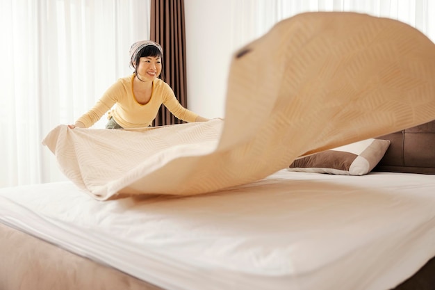 Foto een waardige japanse vrouw die haar bed in een slaapkamer maakt.