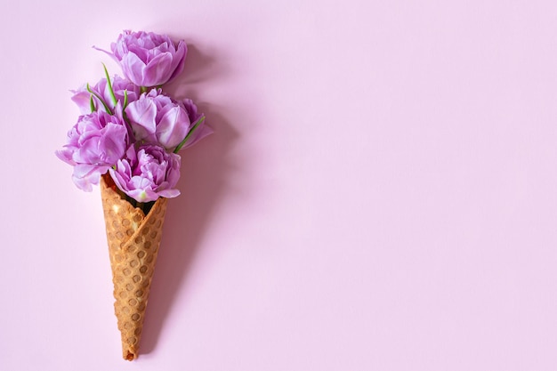 Een wafelkegel van bloemen met een roze achtergrond