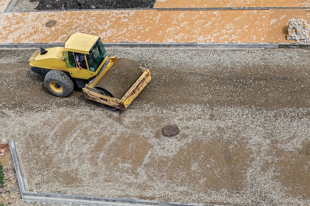 Een wals egaliseert en verdicht zand voordat asfalt op een bouwplaats wordt gelegd
