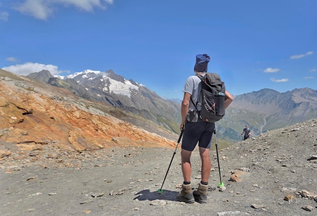 Een wandelaar die in de zomer op het spoor van de Mont Blanc staat en de gletsjers ver weg kijkt