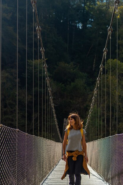 Een wandelaar met een gele rugzak die de Holtzarte-hangbrug oversteekt, Larrau. In het bos of de jungle van Irati, Pyrénées-Atlantiques van Frankrijk