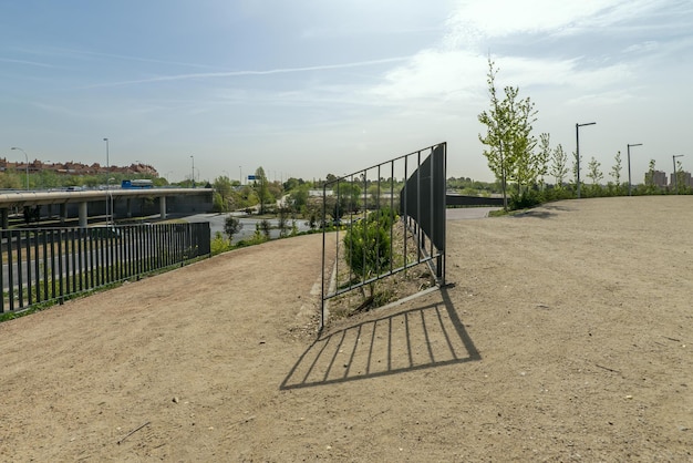 Een wandelpad met zandbestrating in een bocht en metalen reling in een nieuw stadspark