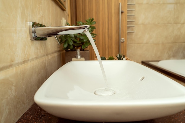 Een water dat van de kraan in de gootsteen loopt in een moderne badkamer