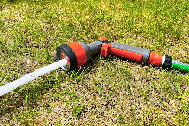 Een waterpistool met een slang ligt op het gras in de tuin een watersproeier om planten water te geven