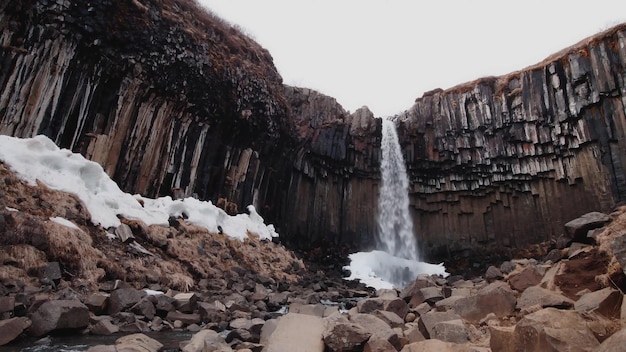 Een waterval in ijsland met sneeuw op de rotsen