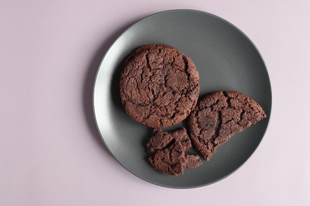 Een weergave van bovenaf op een donkere keramische plaat met chocoladeschilferkoekjes. lila achtergrond.