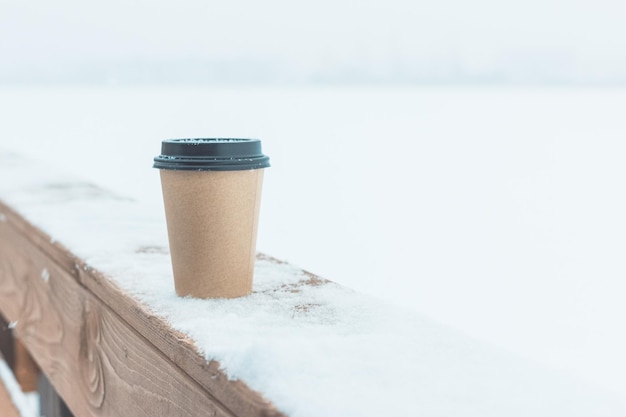 Een wegwerp koffiekopje op de sneeuw op een houten bord.