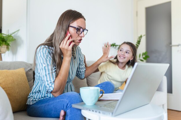 Een werkende moeder die aan het multitasken is. alleenstaande moeder met een kind dat probeert te werken. bezorgde vrouw die thuis werkt terwijl haar dochter haar niet toelaat. quarantaine-isolatie tijdens de covid-19 gezondheidscrisis