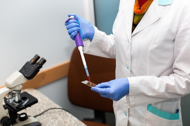 Een wetenschapper die werkt met bloedmonsters en een microscoop in het laboratorium