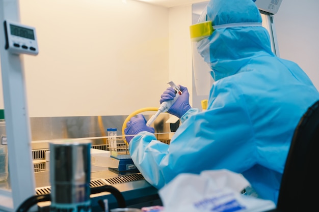 Foto een wetenschapper in ppe-veiligheid, uniform pipetteermonsterexperiment in biologische veiligheidskast (bsc).