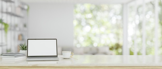 Een whitescreen laptop mockup op een witte tafel boven een wazige moderne heldere woonkamer