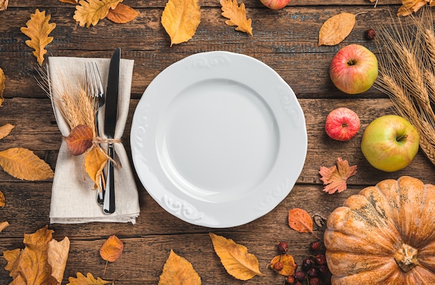 Een wit bestek met een servet op een feestelijke achtergrond met pompoenappels en herfstbladeren