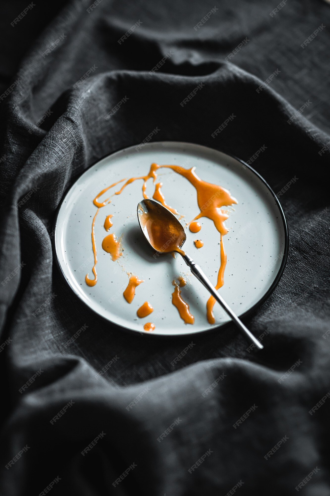 Verduisteren Van toepassing zijn kwaliteit Een wit bord met druppels zelfgemaakte gezouten karamel en een theelepel,  grijs linnen tafelkleed | Premium Foto