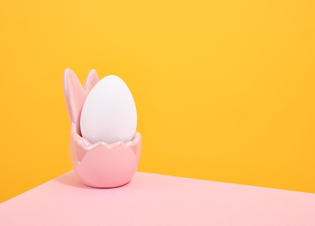 Een wit kippen ei in een roze feestelijke stand Kopieer ruimte voor tekst