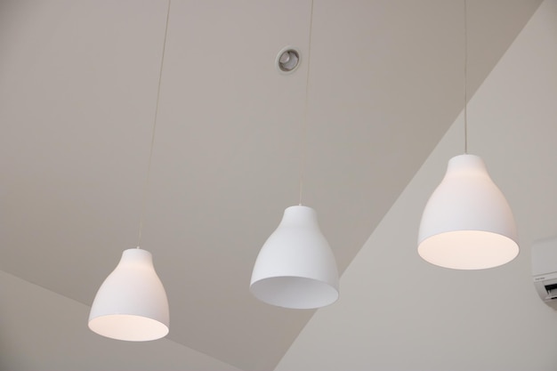 Foto een wit plafond met aan het plafond drie witte lampen.