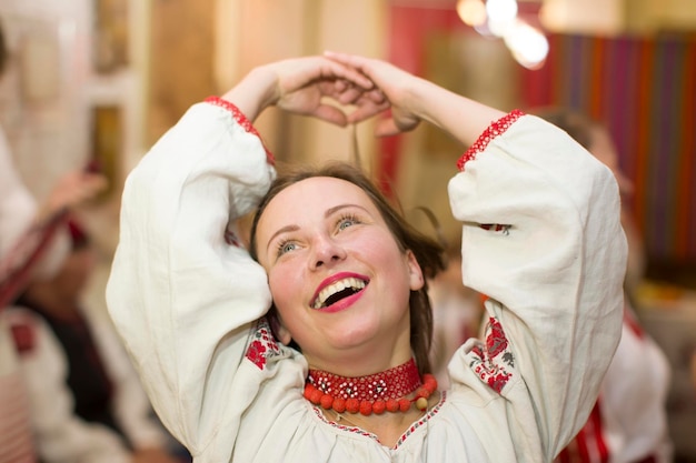 Foto een wit-russische of oekraïense vrouw in een geborduurd overhemd lacht en danst