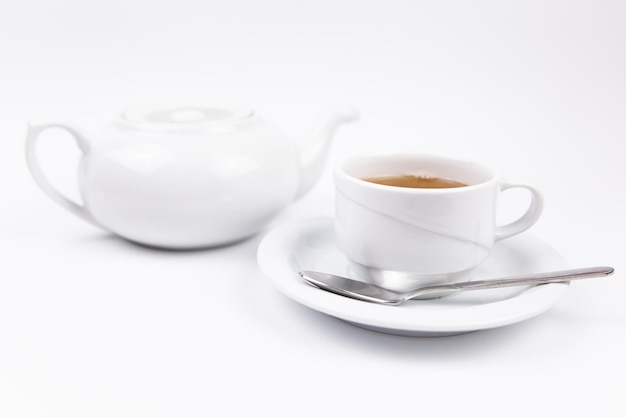 Een wit theeservies met theepot, thee en schotels en taart voor het ontbijt