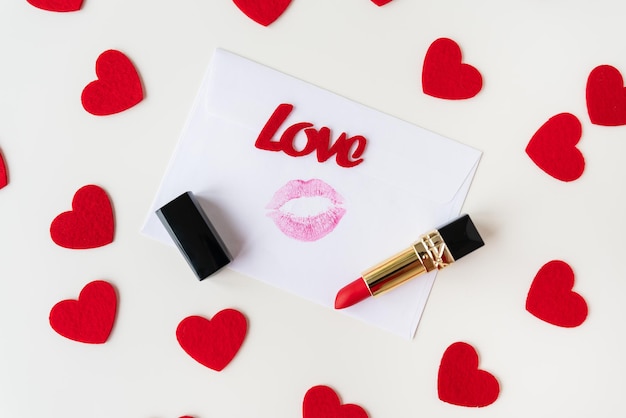 Een witte envelop met een lipafdruk van rode lippenstift op een achtergrond van kleine rode hartjes 14 februari Valentijnsdag concept