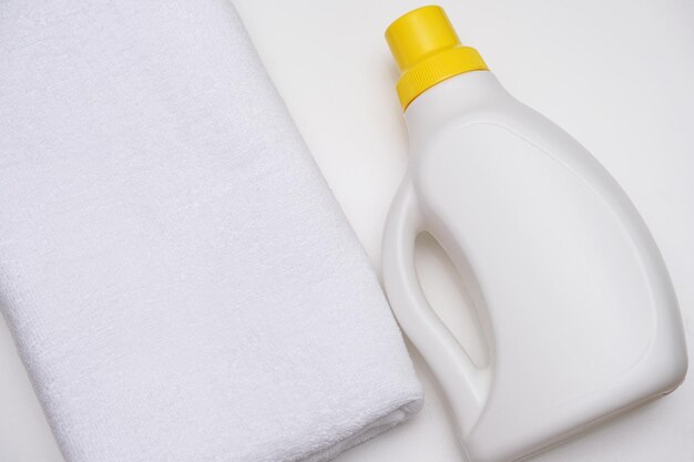 Foto een witte fles met vloeibaar detergent naast een witte terry handdoek huishoudelijke chemicaliën
