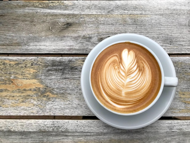 Een witte kop cappuccino met latte art op houten tafel achtergrond