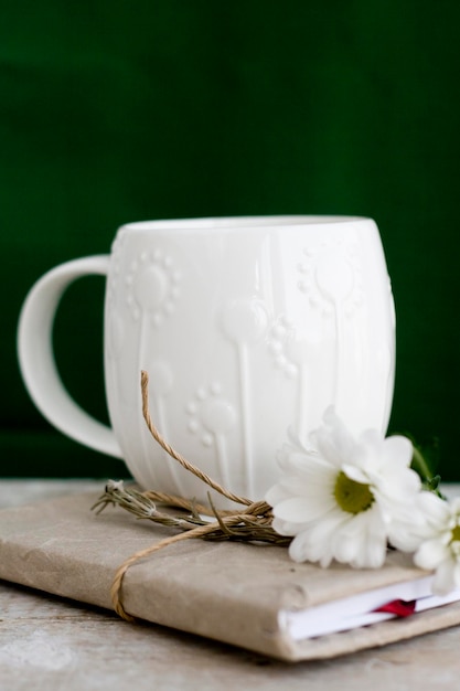 Een witte kop op een groene achtergrond en vintage notitieboekje