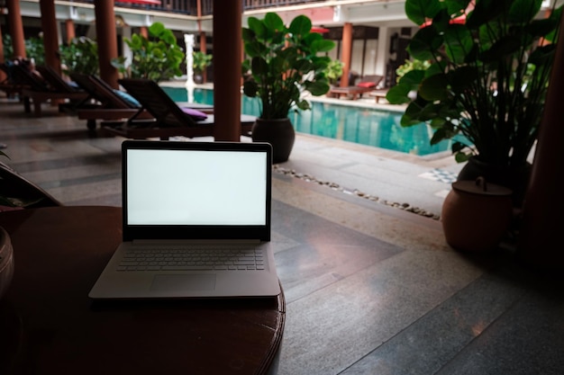 Een witte laptop op houten tafel zwembad achtergrond