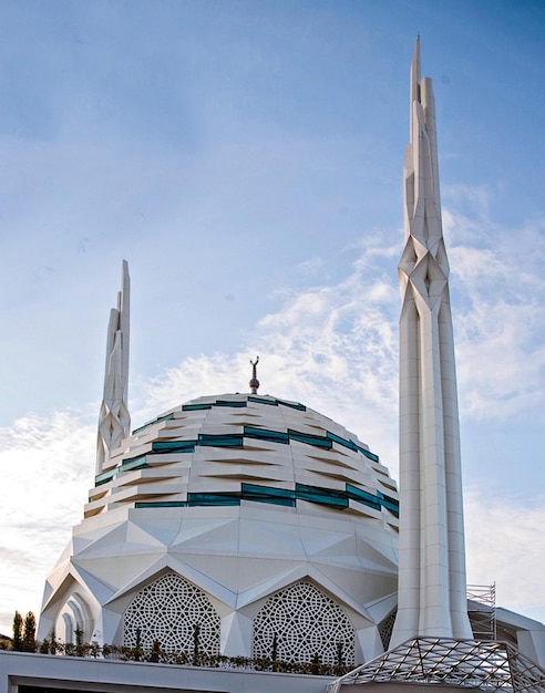 Een witte moskee met een blauwe lucht op de achtergrond
