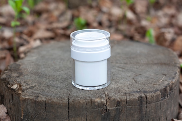 Een witte pot cosmetica op een gekapte boom in het bos