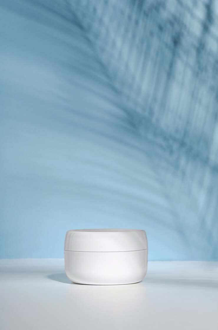 Foto een witte pot crème op een stand, op een witte tafel met tropische palmbladeren en hun schaduw.