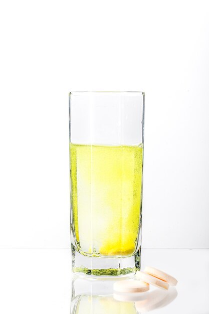 Een witte tablet lost op in een glas water en kleurt het water geel