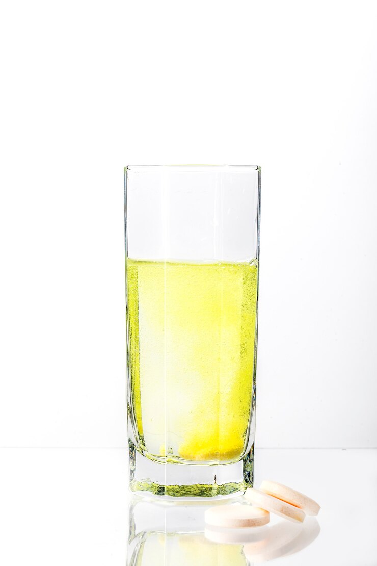 Een witte tablet lost op in een glas water en kleurt het water geel