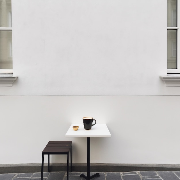 Een witte tafel met daarop een zwarte koffiekop