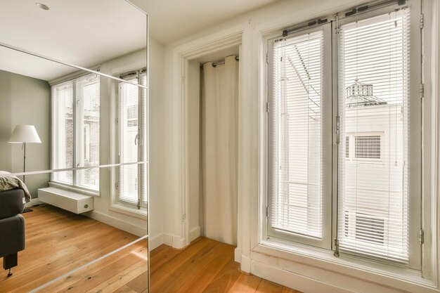 Foto een woonkamer met houten vloeren en witte luiken voor de ramen die uitkijken op een buitenpatio