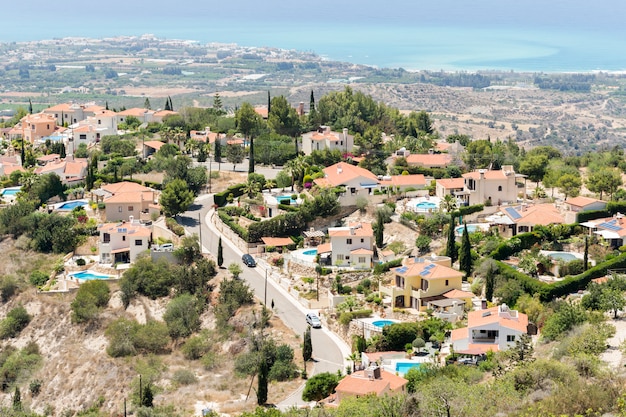 Een woonwijk met zwembaden, huizen gelegen op een heuvel met uitzicht op zee