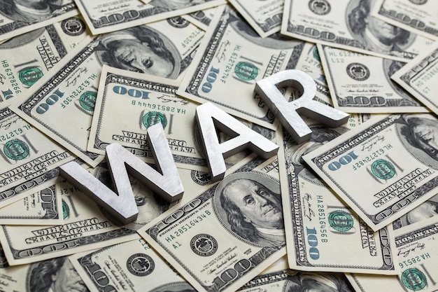 Foto een woordoorlog gelegd door metalen letters op de achtergrond van dollarbankbiljetten
