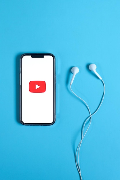 Een Youtube-logo op het smartphonescherm met oortelefoon