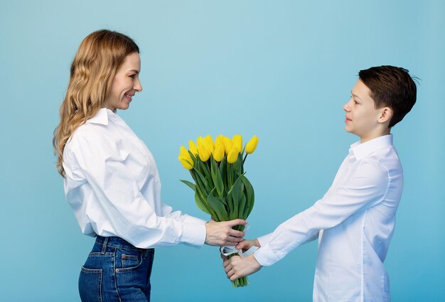 Een zachtaardige zoon feliciteert een gelukkige moeder en geeft haar een boeket tulpen