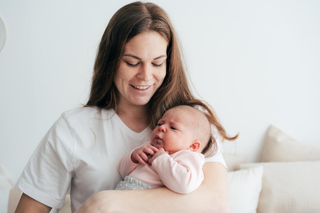 Een zachte, zorgzame moeder houdt een pasgeboren baby in haar armen